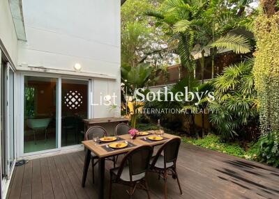 Outdoor patio area with dining table and lush greenery