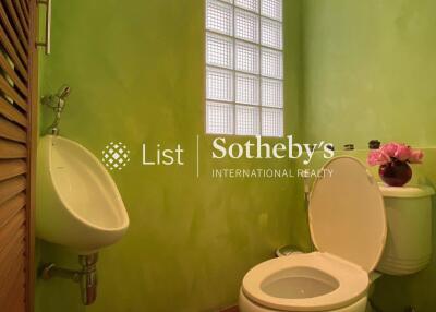 Small bathroom with green walls and a glass block window