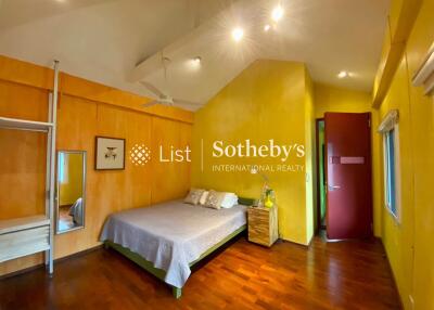 Spacious bedroom with wooden floor and yellow walls