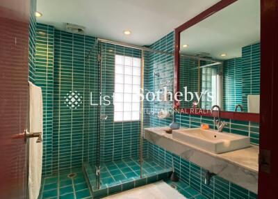 Modern bathroom with blue tiles, a large mirror, and a glass-enclosed shower