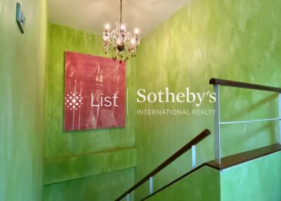 staircase with green walls and chandelier