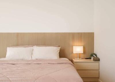 Modern bedroom with double bed, wooden headboard, bedside table, and lamp