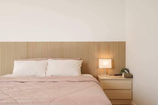 Modern bedroom with double bed, wooden headboard, bedside table, and lamp