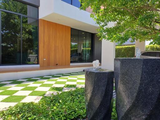 Modern building facade with green lawn and stylish stone water features