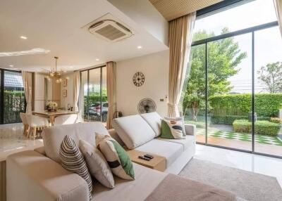 Spacious and bright living room with large windows, modern furniture, and garden view