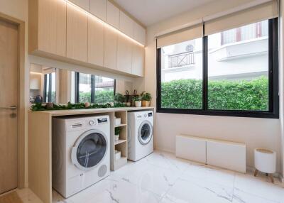 Modern laundry room with washer and dryer, cabinets, and large window