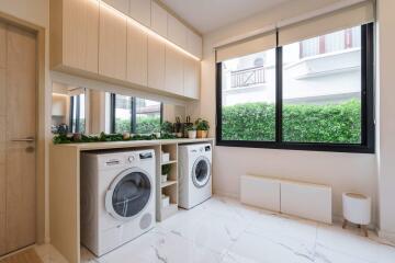 Modern laundry room with washer and dryer, cabinets, and large window