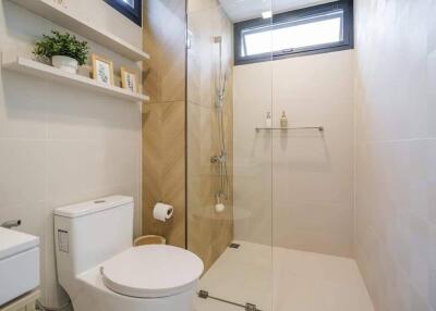 Modern bathroom with glass shower, toilet, and wall shelf