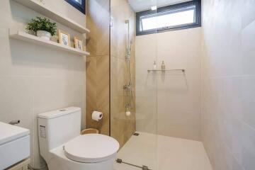 Modern bathroom with glass shower, toilet, and wall shelf