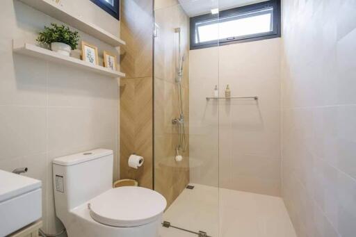 Modern bathroom with glass shower, toilet, and wall shelf