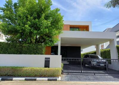 Modern two-story house with carport and surrounding greenery