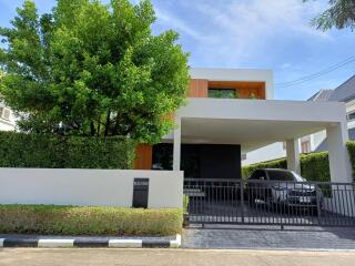 Modern two-story house with carport and surrounding greenery