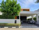 Modern two-story house with carport and surrounding greenery