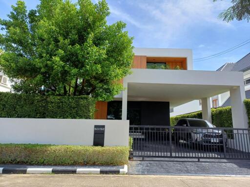 Modern two-story house with carport and surrounding greenery