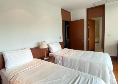 Twin beds in a well-lit bedroom with wooden elements