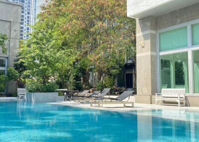 Outdoor pool area with lounge chairs and surrounding greenery