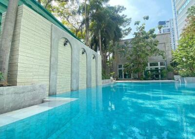 Outdoor swimming pool in a landscaped area with building in the background