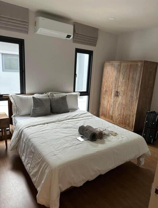 Bedroom with bed, air conditioning, windows, wooden wardrobe, and bedside table