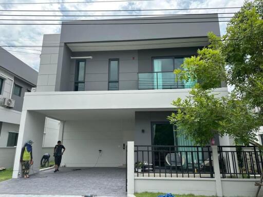 Modern two-story house with people working outside