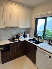 A modern kitchen with white cabinets and marble backsplash