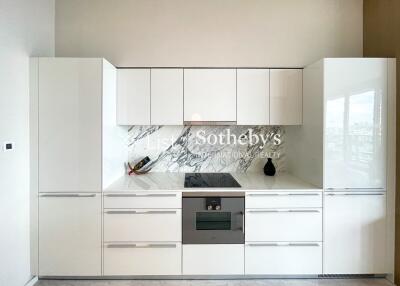 Modern white kitchen with integrated appliances and marble backsplash