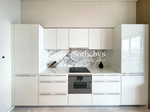 Modern white kitchen with integrated appliances and marble backsplash