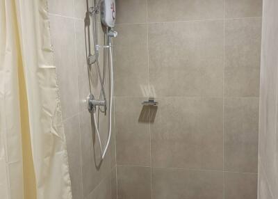 Shower area with beige tiles and curtain