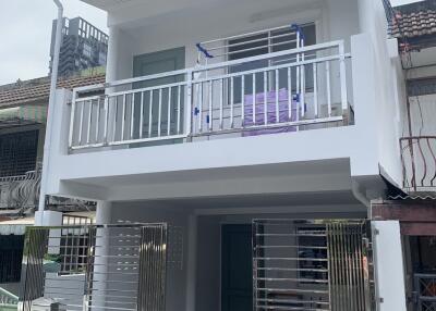 Two-story white building with a balcony and metal gate