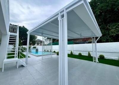 Modern outdoor patio with stairs leading to raised platform, overlooking a swimming pool