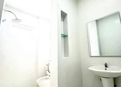 A bright and modern bathroom with a sink, mirror, and shower area