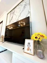 Modern living room with marble accent wall, large TV, and decorative items