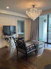 Modern living room with elegant chandelier and glass doors to balcony