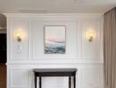 Elegant wall paneling with wall sconces and a decorative console table beneath a framed artwork