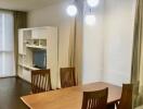 Dining area with wooden table and chairs, adjacent to living space with shelving unit