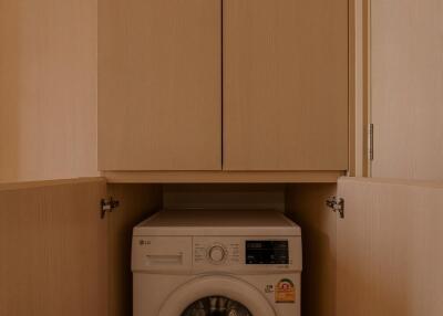 Small laundry area with built-in washer and storage cabinets