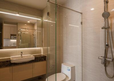 Modern bathroom with glass shower, toilet, and vanity