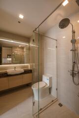 Modern bathroom with glass shower, toilet, and vanity