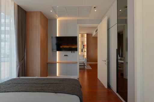 modern bedroom with mounted TV and wooden flooring