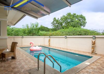 Outdoor area with swimming pool, seating, and greenery