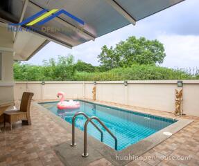 Outdoor area with swimming pool, seating, and greenery