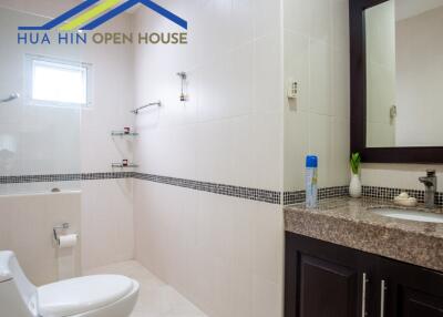 Modern bathroom with white tiles, a toilet, and a sink with a mirror