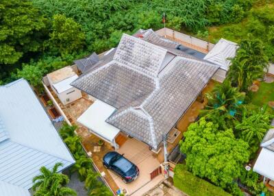 Aerial view of a residential house with lush greenery in the background