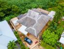 Aerial view of a residential house with lush greenery in the background