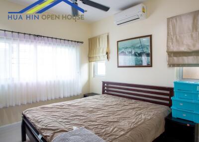 Bedroom with double bed, air conditioning, and large windows with curtains