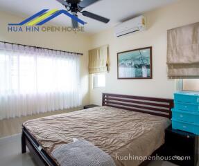 Bedroom with double bed, air conditioning, and large windows with curtains