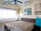 Bedroom with double bed, air conditioning, and large windows with curtains