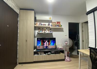 Living room with wooden cabinets, TV, fan, and shelves with collectibles