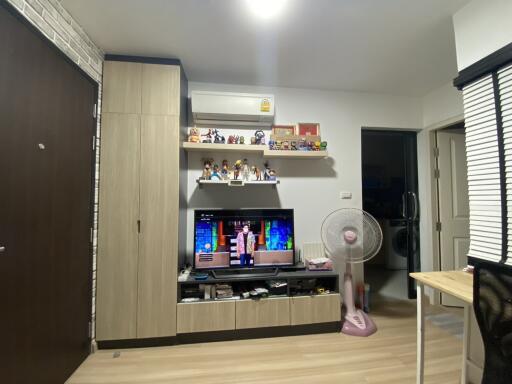 Living room with wooden cabinets, TV, fan, and shelves with collectibles