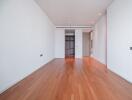 Spacious empty bedroom with wooden flooring and built-in wardrobe