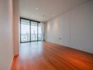 Spacious living room with wooden flooring and large floor-to-ceiling windows.